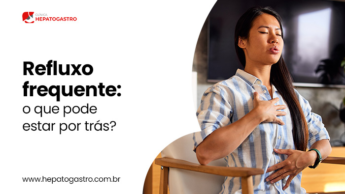 Refluxo Frequente: O Que Pode Estar Por Trás? 1 Mulher Sentada Com A Mão No Peito E No Abdômen, Aparentando Desconforto Relacionado A Refluxo Ou Azia.