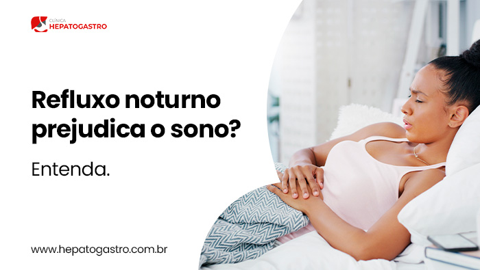 Refluxo Noturno Prejudica O Sono? Entenda 1 Mulher Deitada Na Cama Com As Mãos Sobre O Abdômen, Demonstrando Desconforto Causado Por Refluxo Noturno Durante O Sono.